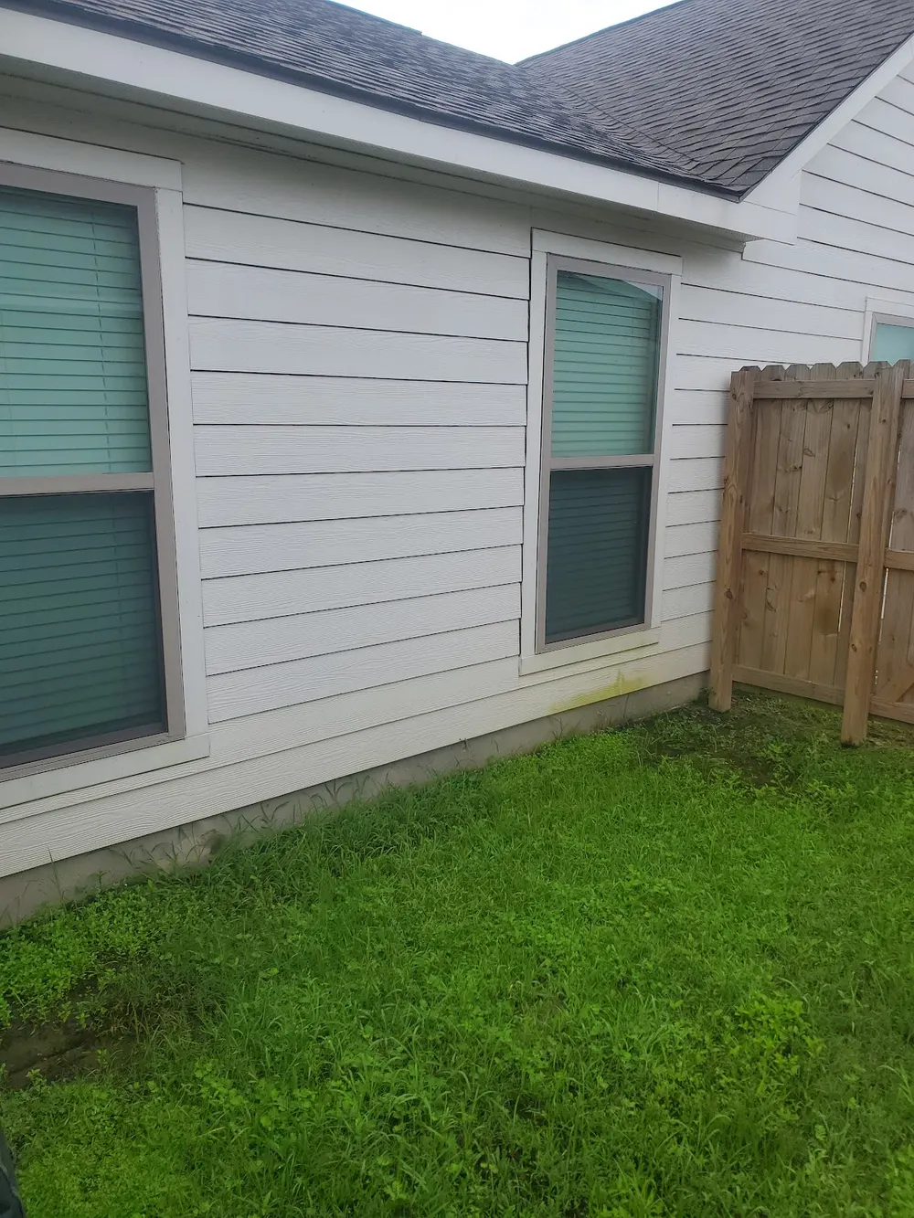 A wood privacy fence beside a washed section of house siding
