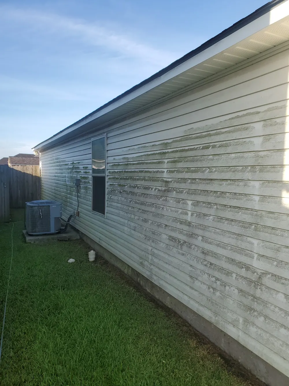 Dirt at the base of mobile-home-style siding before a wash