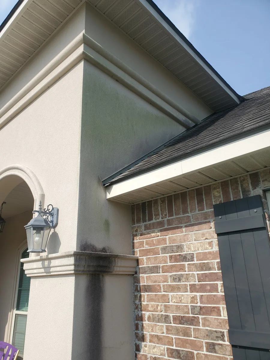 Mildew-streaked stucco archway before cleaning