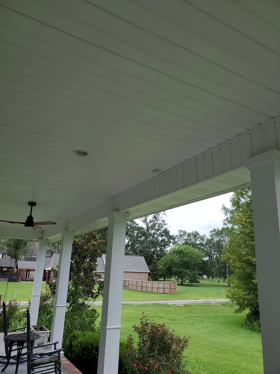 A covered porch with a clean white ceiling, columns and fans